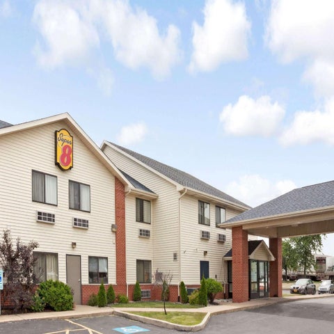 A Super 8 motel is shown with a covered entrance and a brick facade under a partly cloudy sky.