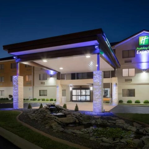 A Holiday Inn Express building facade is illuminated at dusk, featuring a covered entrance and landscaped front.