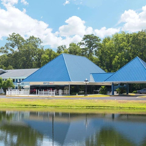 A low-angle view showcases a hotel with a distinctive blue, peaked roof and a pond in the foreground.