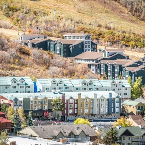A hillside resort complex features colorful buildings with varied architectural styles and a mix of residential and commercial structures.