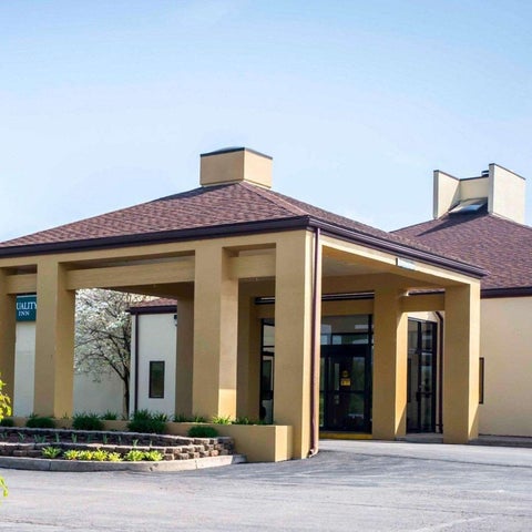 The front entrance of a Quality Inn hotel features a covered walkway and a brick facade with multiple doors.