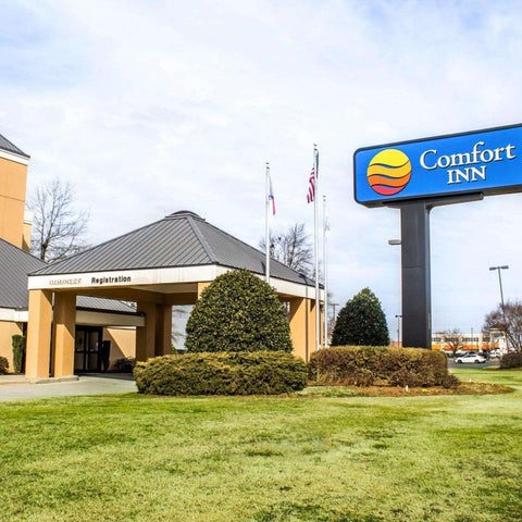 The front of a Comfort Inn hotel is shown with its registration area and signage against a cloudy sky.