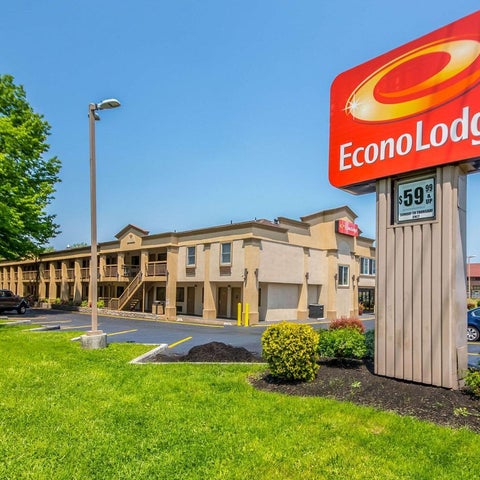 An Econo Lodge motel building is shown with its sign and a grassy lawn in front of it on a sunny day.