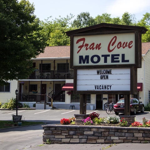 Fran Cove Motel features a sign displaying 'Open' and 'Vacancy' alongside a yellow building and landscaped front.