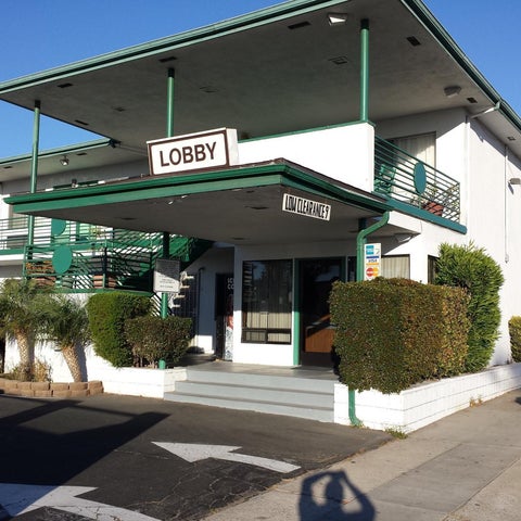 The front entrance of a motel features a covered lobby area with a 'Lobby' sign and green accents.