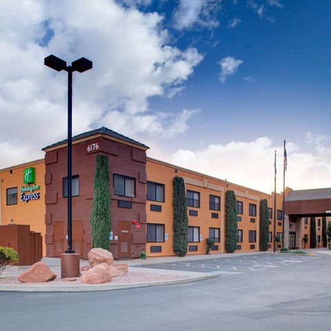 A multi-story Holiday Inn Express hotel is shown with a parking lot, landscaping, and a cloudy sky in the background.