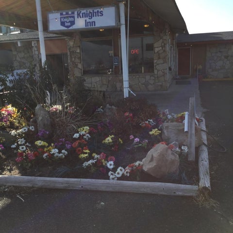 The stone facade of Knights Inn features a sign, landscaping, and a covered entrance with windows and doors.