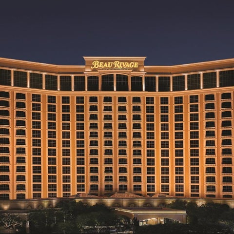 The Beau Rivage hotel and casino building is illuminated at night, showcasing its curved facade and numerous windows.
