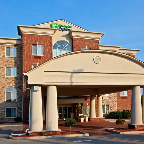A Holiday Inn Express hotel features a brick facade, prominent entryway with columns, and a covered drop-off area.