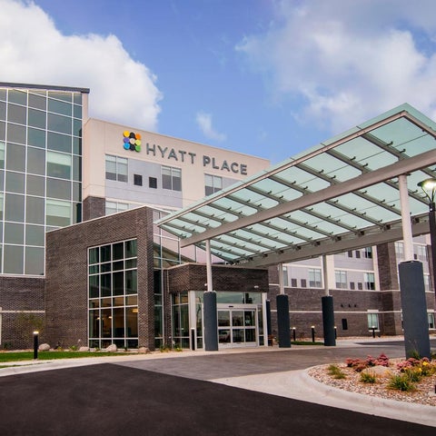 A Hyatt Place hotel features a modern facade with a covered entrance and a large glass window.