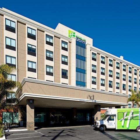 A Holiday Inn Express hotel building with a multi-story facade, parking lot, and a delivery truck in front.