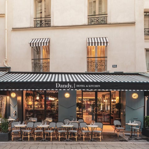 Dandy Hotel & Kitchen features a striped awning, outdoor seating, and a modern facade with large windows.