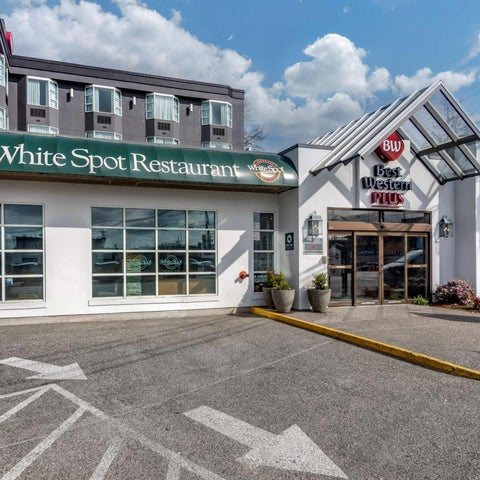 The exterior of the Best Western Plus hotel and White Spot Restaurant, featuring a parking lot and signage.