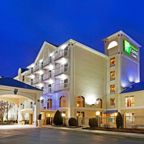 A brightly lit Holiday Inn Express hotel stands against a twilight sky, featuring a covered entrance and landscaped grounds.