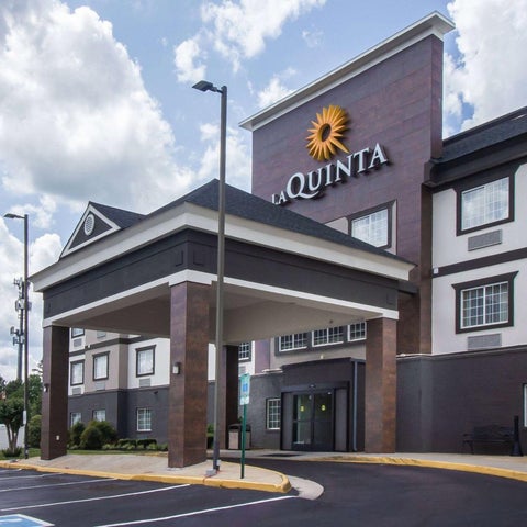 A La Quinta Inn & Suites building facade features a prominent logo, covered entrance, and parking lot.