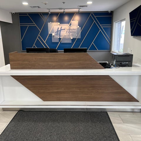 The lobby of a Holiday Inn Express features a modern reception desk with a geometric blue and gold accent wall.