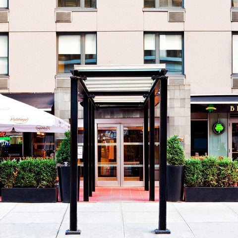 A building entrance features a covered walkway, umbrella, planters, and a 'brew house' sign.