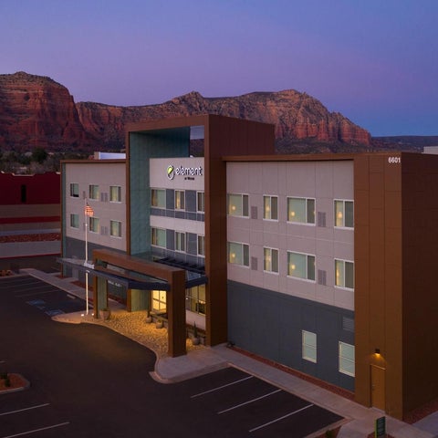 An element hotel with a modern design sits against a backdrop of red rock formations at dusk.