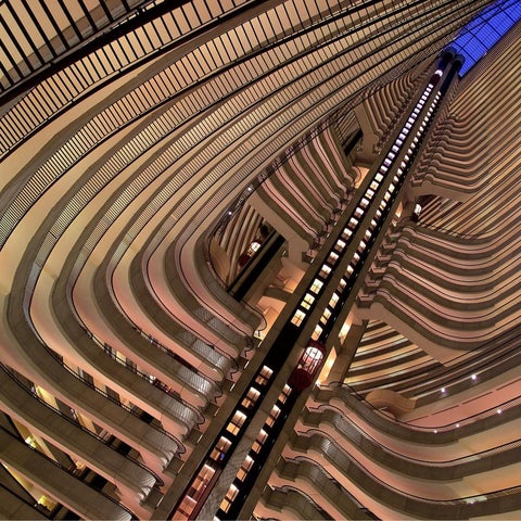An interior view of a multi-story building with curved, layered balconies and a central elevator shaft.