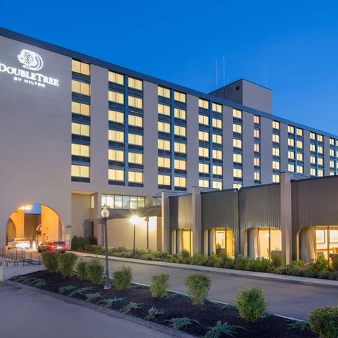 A multi-story DoubleTree by Hilton hotel building is shown with a well-manicured landscape and parking area in front.