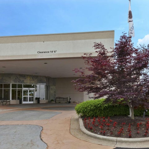 A building facade with a covered entrance, landscaping, an American flag, and a decorative flag.