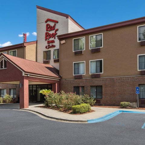 A Red Roof Inn & Suites building facade shows a three-story brick structure with a covered entrance and parking lot.