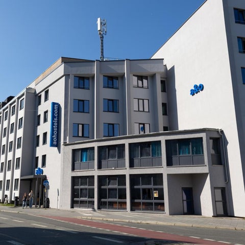 A large, modern hotel building with a communications tower and a street with traffic in front of it.
