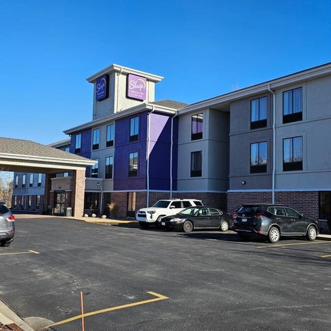 A multi-story La Quinta Inn & Suites building with a parking lot and several cars parked in front of it on a sunny day.