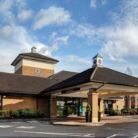 A hotel entrance with a peaked roof and a sign visible, set against a partly cloudy sky.