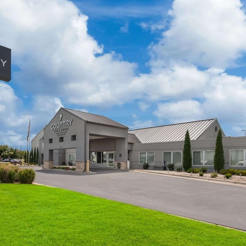 A Country Inn & Suites building features a gray facade, covered entryway, and manicured lawn with a prominent sign.