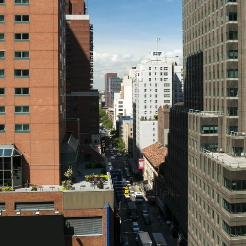 A high-angle view showcases a dense urban street scene lined with tall, varied office buildings and bustling traffic.