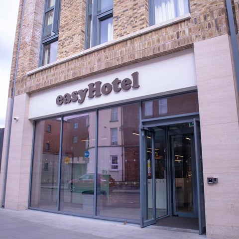 The entrance of an easyHotel features a large glass facade and a prominent hotel sign.