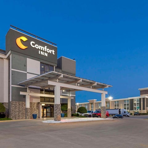 A Comfort Inn hotel building is shown at dusk with a sign and parking lot visible in the foreground.
