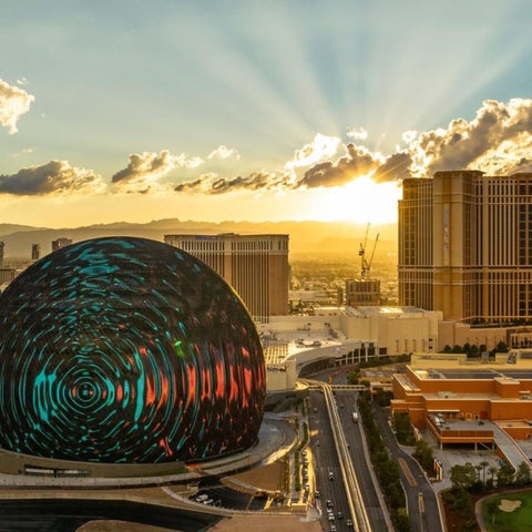 An aerial view showcases the Sphere and surrounding buildings of a large resort complex at sunset.