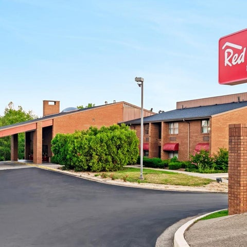 A Red Roof Inn & Suites building features a brick facade, covered entryway, and a sign with the hotel's logo.