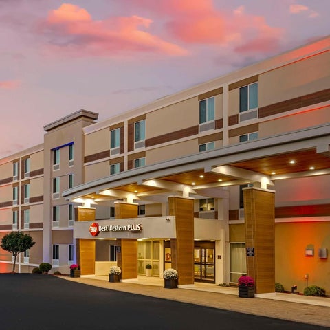 A Best Western Plus hotel facade is shown at dusk with a covered entrance and landscaped front.