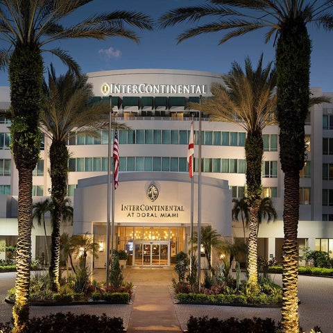 The InterContinental at Doral Miami features a modern facade with palm trees, flags, and a well-manicured entrance.