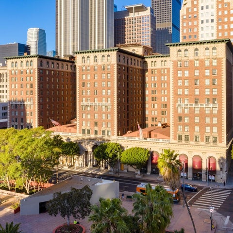 An elevated view showcases a large, ornate brick building with a classical facade and surrounding greenery in an urban setting.