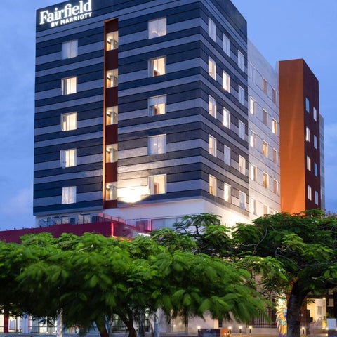 A modern Fairfield by Marriott hotel building with a striped facade and orange accent features is shown at dusk.