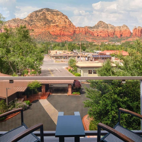 A balcony view overlooks a hotel complex and lush greenery with a distant mountain range backdrop.