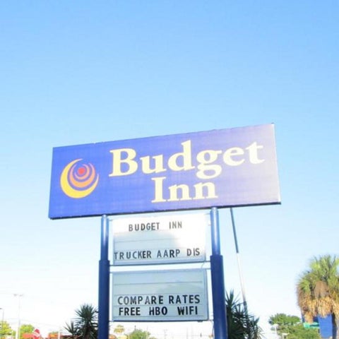 A blue and white sign advertises the Budget Inn, highlighting free HBO, WiFi, and rates for truckers and AARP members.