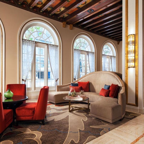 A luxurious lobby features arched windows, a curved sofa, modern chairs, and a patterned rug with elegant decor.