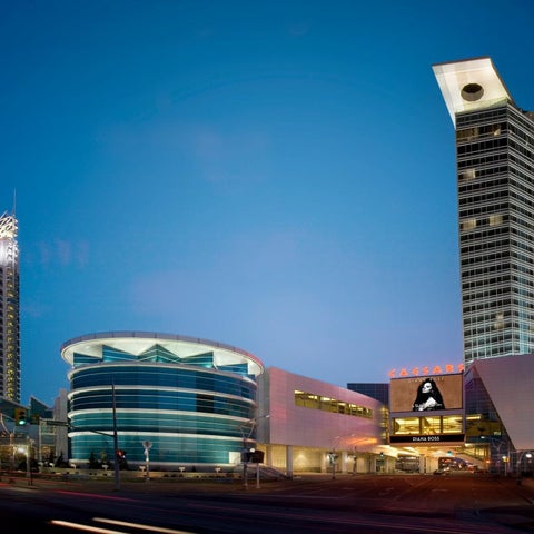 An exterior view of Caesars Palace and surrounding buildings at dusk, showcasing their distinctive architecture and illuminated facades.