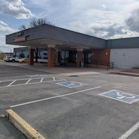 A large, single-story building with a covered entrance and designated parking spaces, including accessible spots, under a cloudy sky.