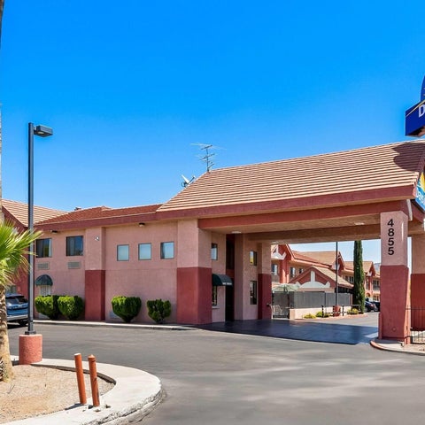 A Days Inn hotel building is shown with a red tile roof, a covered entryway, and a blue and yellow sign.