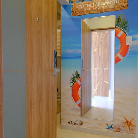 A hotel room features a beach-themed mural and multiple doorways leading to different areas.