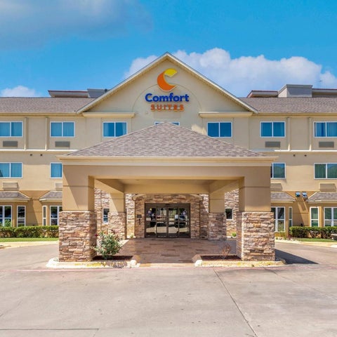 A two-story Comfort Suites hotel building with a stone entrance and a covered driveway under a peaked roof.