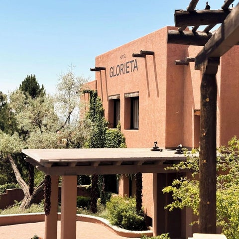 A terracotta-colored building with a wooden overhang and surrounding greenery is partially visible against a clear blue sky.