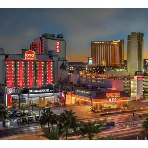 An exterior view of the Oyo Steak & Shake hotel complex with several other buildings and palm trees in the Las Vegas skyline.