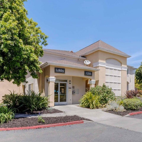 A tan-colored building with a lobby entrance and landscaping features a well-maintained exterior.